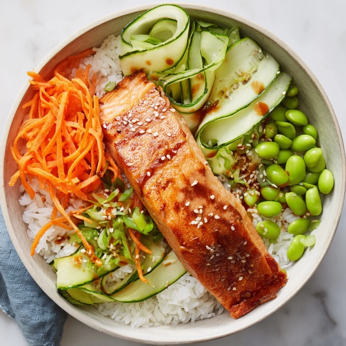 Golden crispy salmon fillet with crackling skin served over fluffy white rice bowl with fresh cucumber, avocado slices, and savory soy ginger sauce drizzle