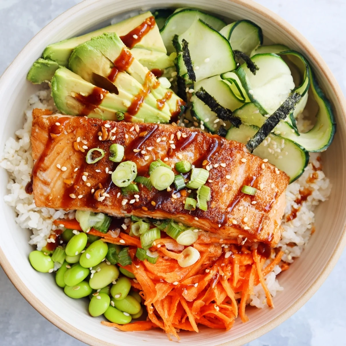 Vibrant Asian-inspired crispy salmon and rice bowl topped with colorful julienned carrots, edamame, scallions, and toasted sesame seeds for a nutritious pescatarian dinner