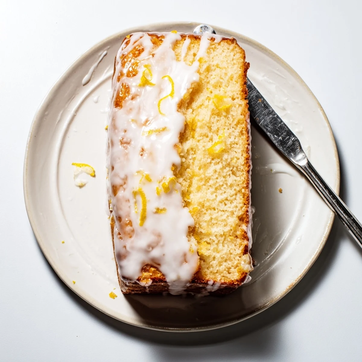 Glazed Greek yogurt lemon loaf bread with powdered sugar dusting and lemon zest garnish
