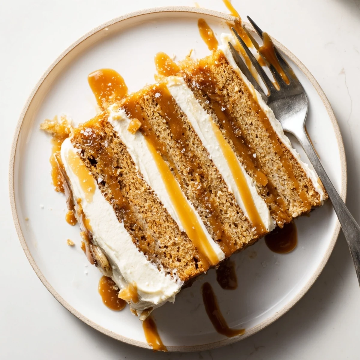 Slice of moist banana cake layered with rich salted caramel sauce and topped with creamy caramel buttercream