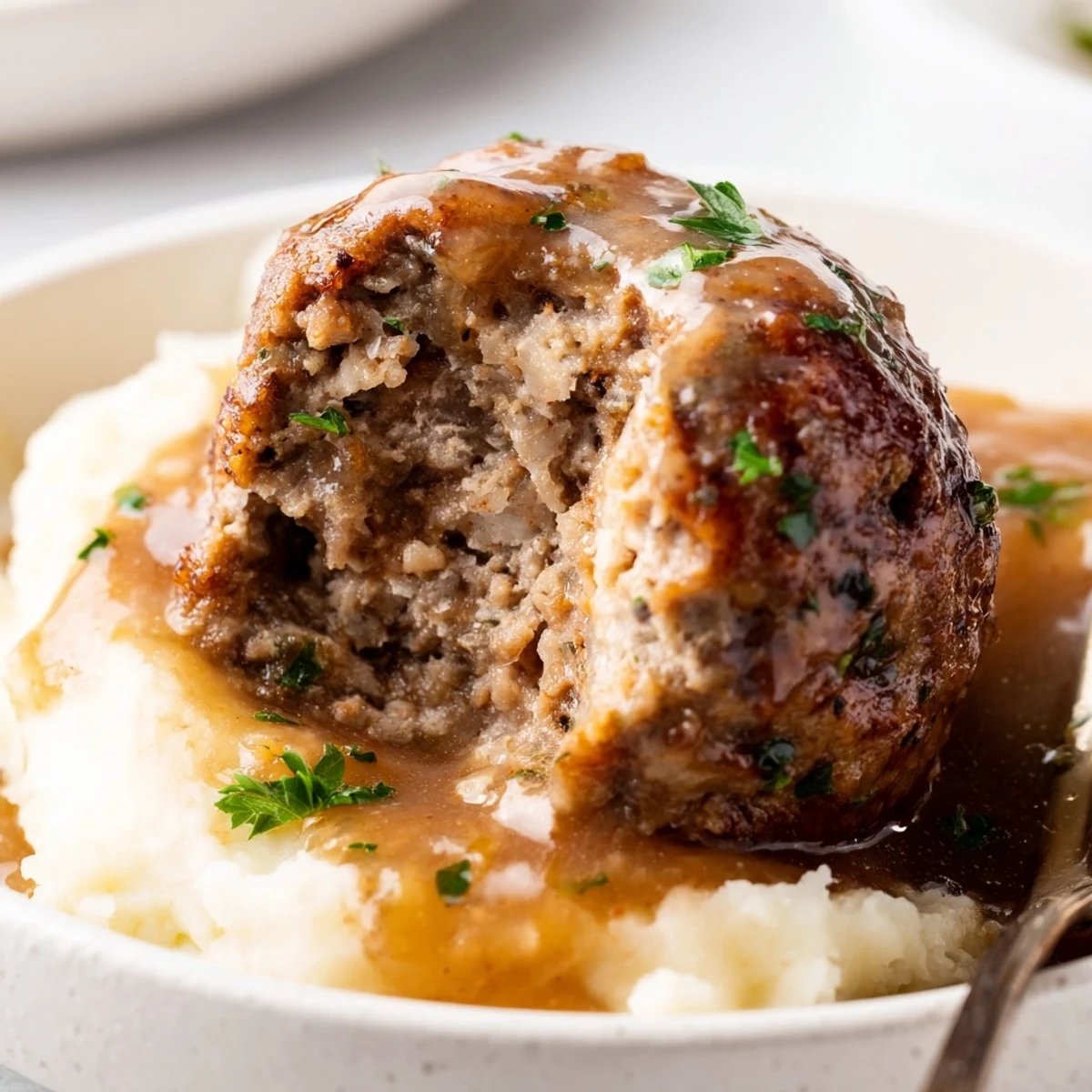 Creamy Crockpot Meatballs Gravy spooned over buttery mashed potatoes, steaming and rich