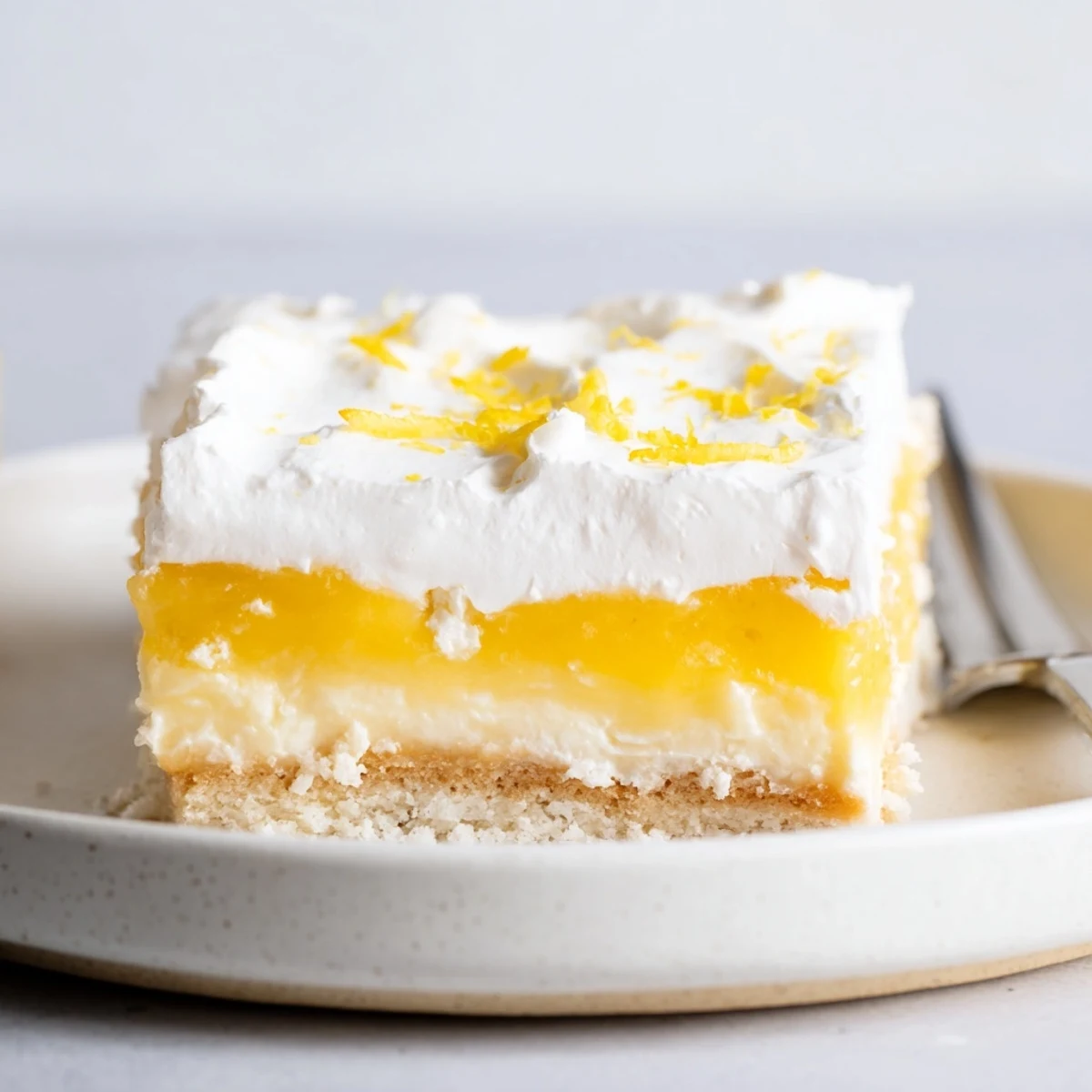 Slice of Lemon Lush Cake showing creamy lemon layer and whipped topping