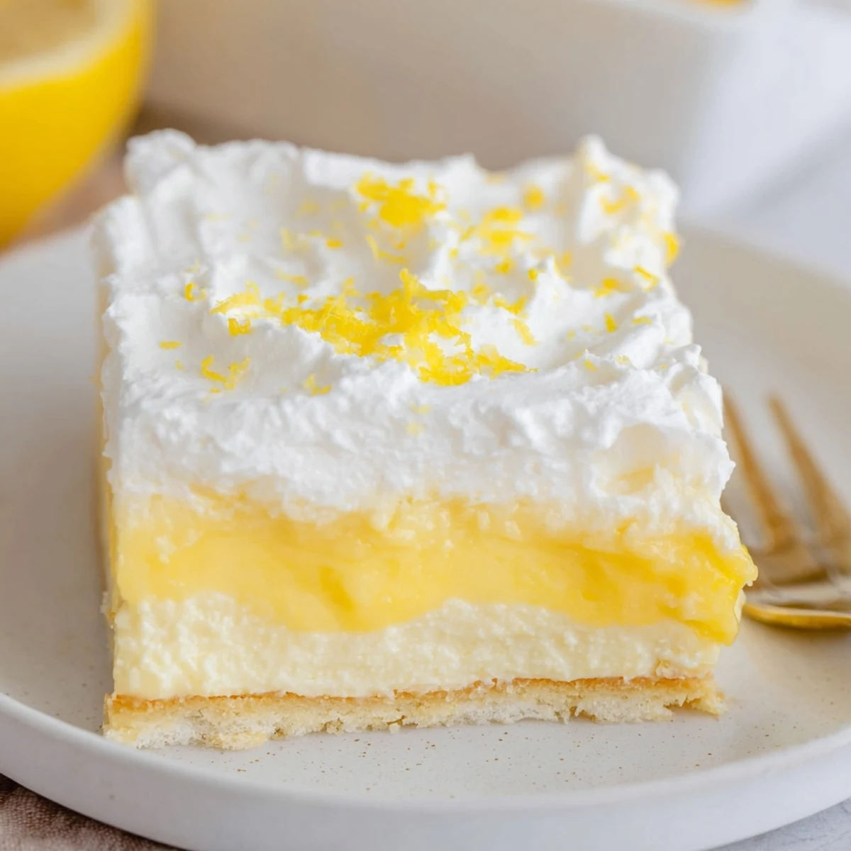 Sliced Lemon Lush Cake on plate, tangy pudding layer, fluffy whipped topping