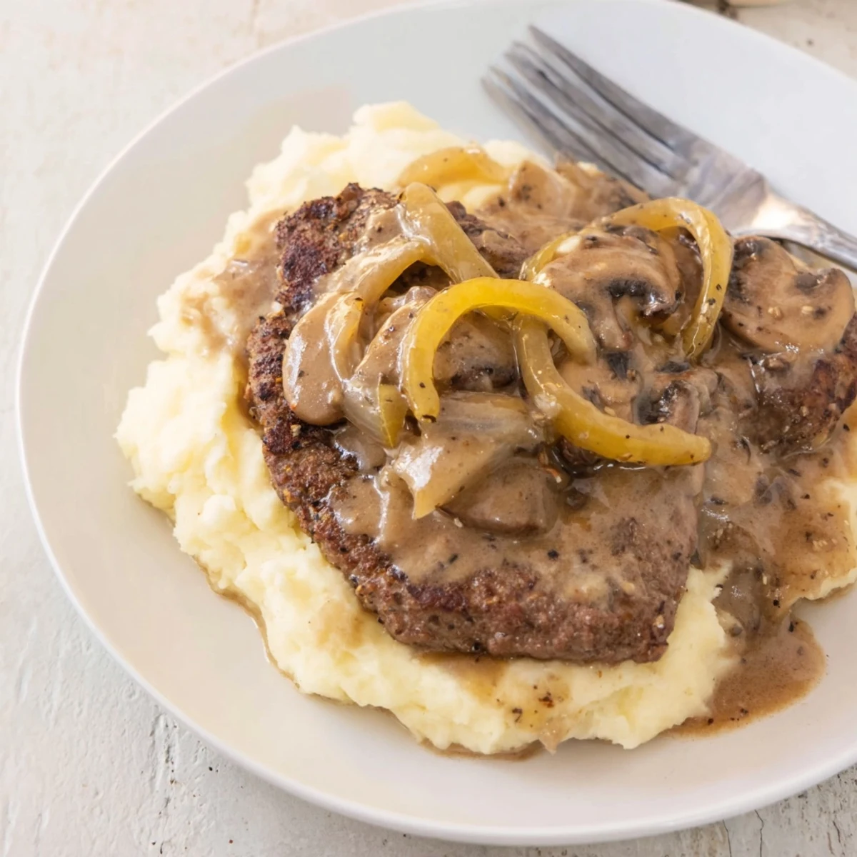 Warm Country Style Smothered Cube Steak Recipe spooned over creamy mashed potatoes