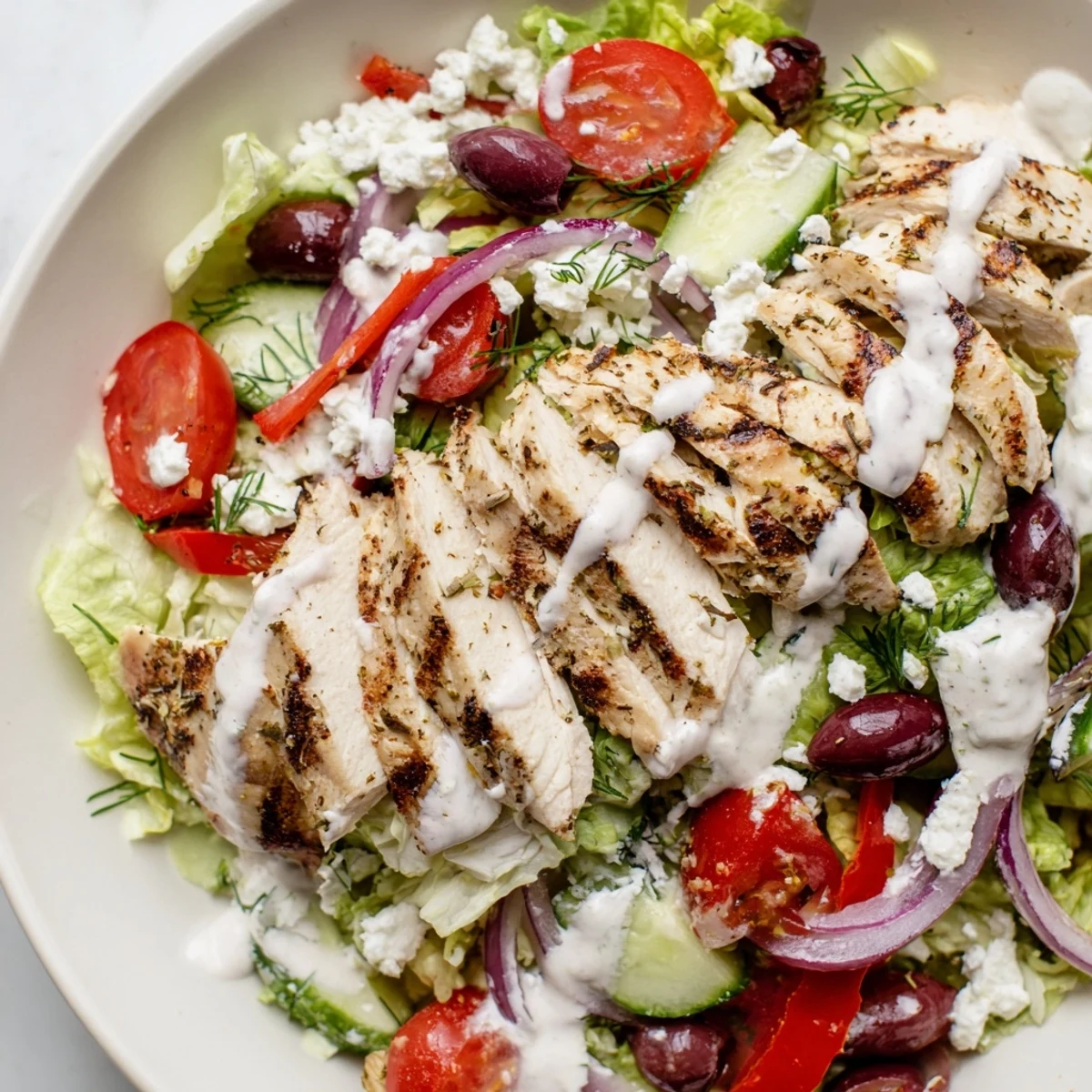 Greek Chicken Salad drizzled with tangy whipped feta over crisp romaine and colorful vegetables