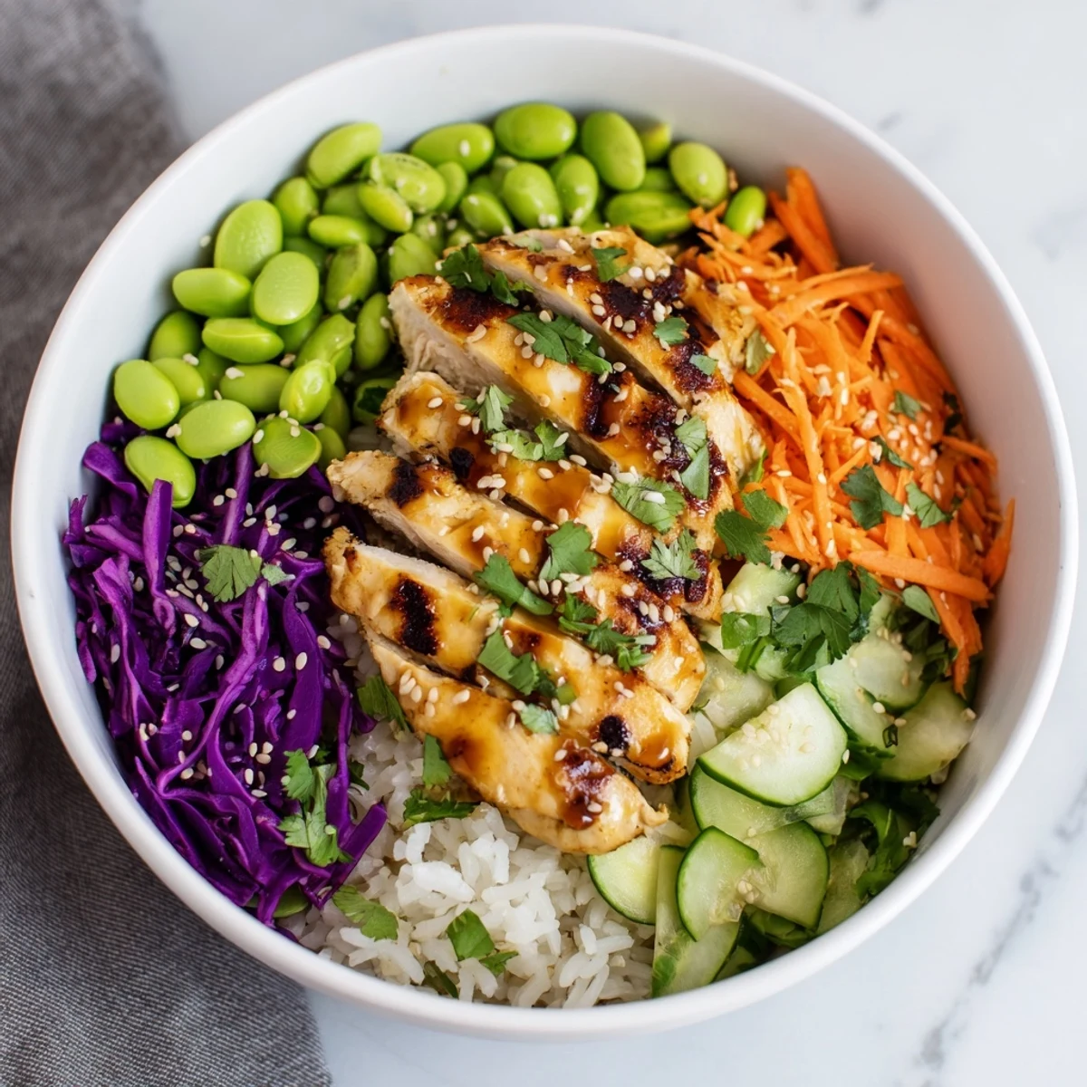 Golden marinated chicken strips arranged over crisp veggies in an Asian-inspired chicken power bowl.