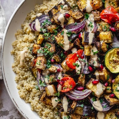 Vibrant eggplant grain bowl topped with pomegranate seeds and zesty dressing
